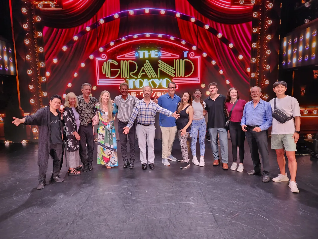 Tour guests on a theater stage with red curtains and an illuminated sign